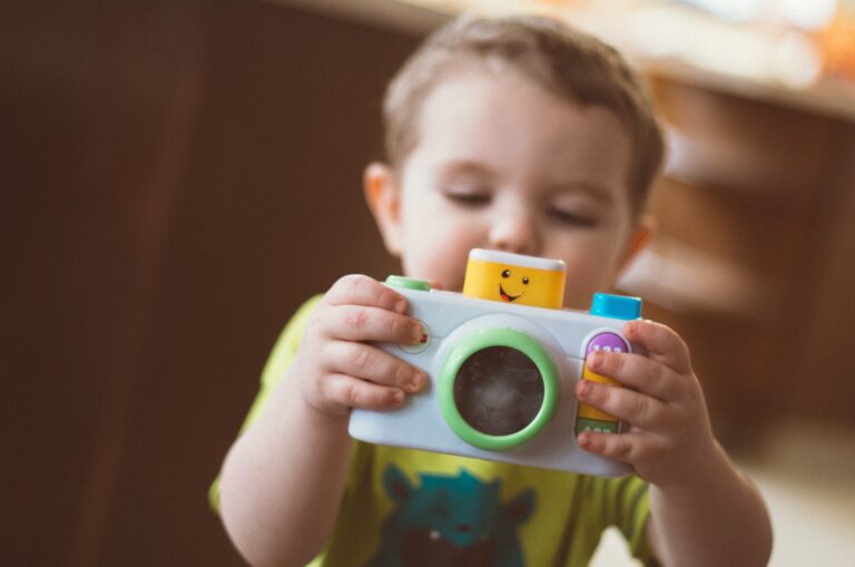 A baby looks at the back of a toy camera