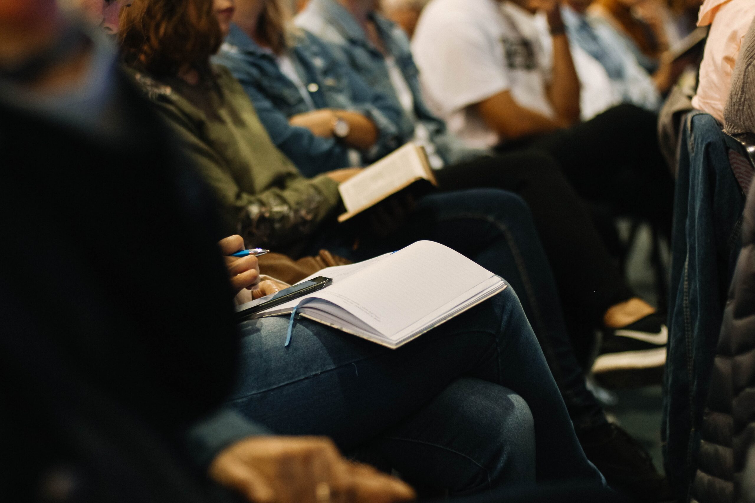 A row of people sitting with notebooks in their laps